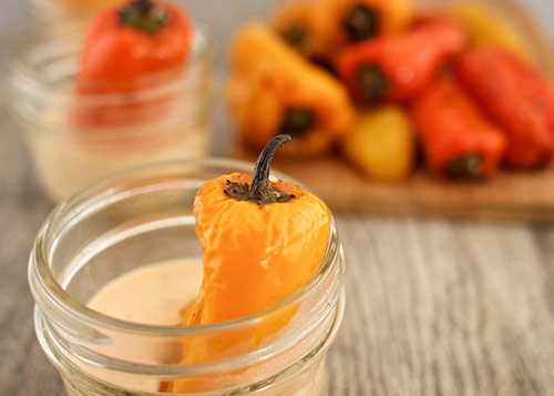 Mini yellow bell pepper, in a sauce, with more peppers in the background